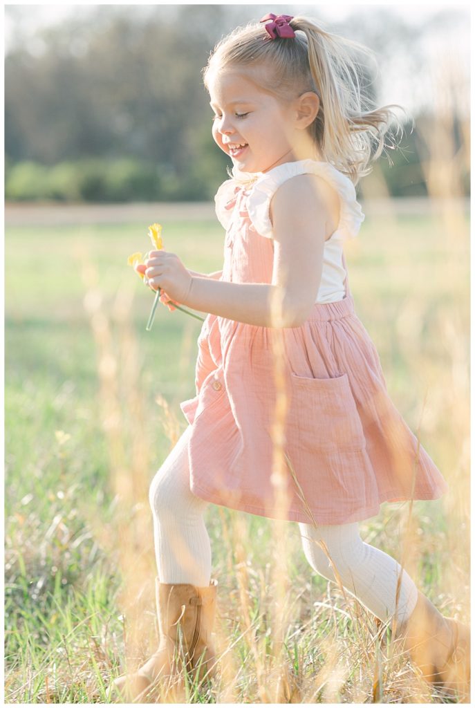 Little girl running in the sun holding flowers