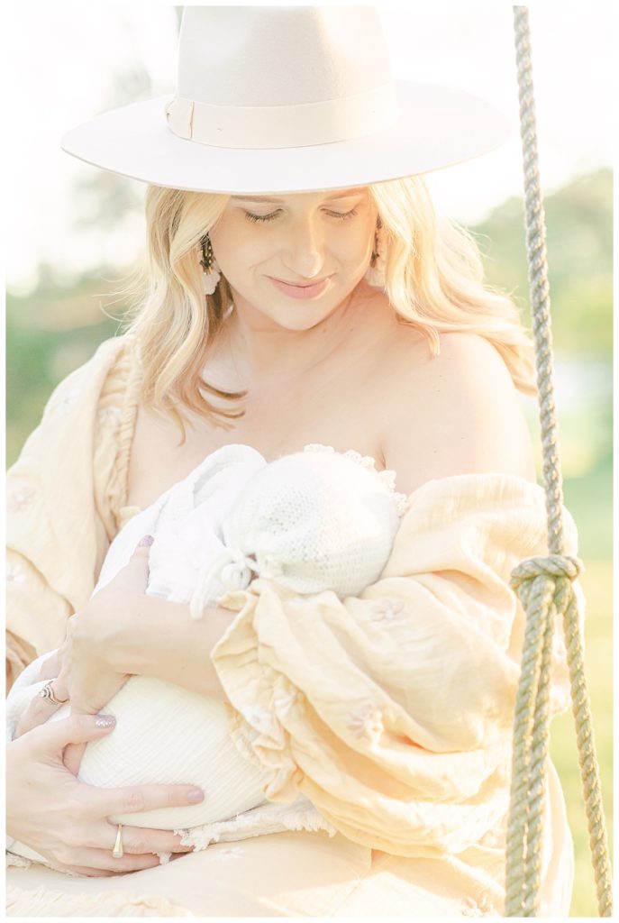 Mom wearing hat looking down and smiling at baby girl