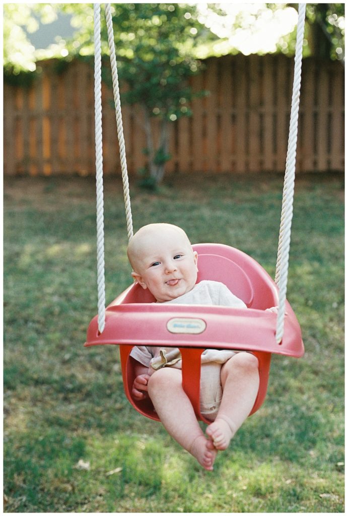 Baby boy swinging in a red swing
