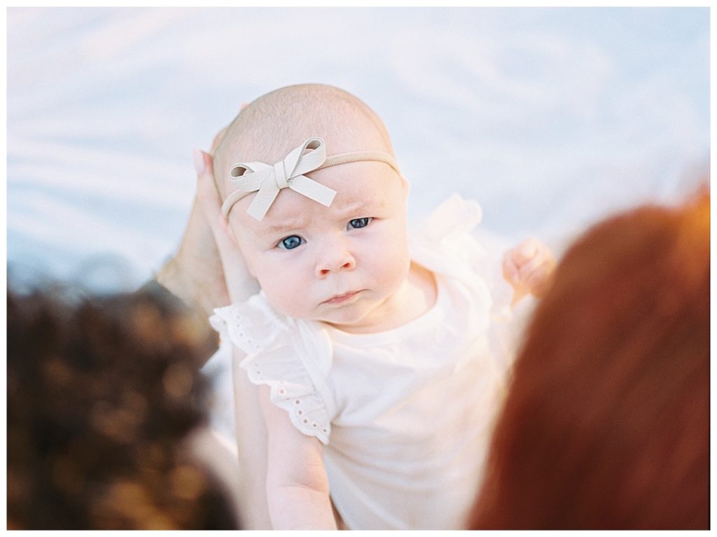 Huntsville, AL newborn photographer, baby girl looking at camera and wearing a light pink bow